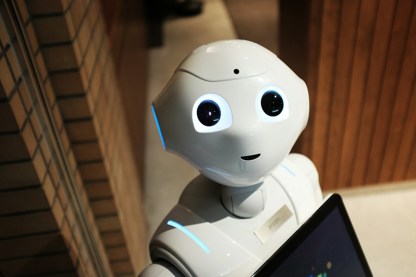 A white humanoid robot with round eyes holding a tablet