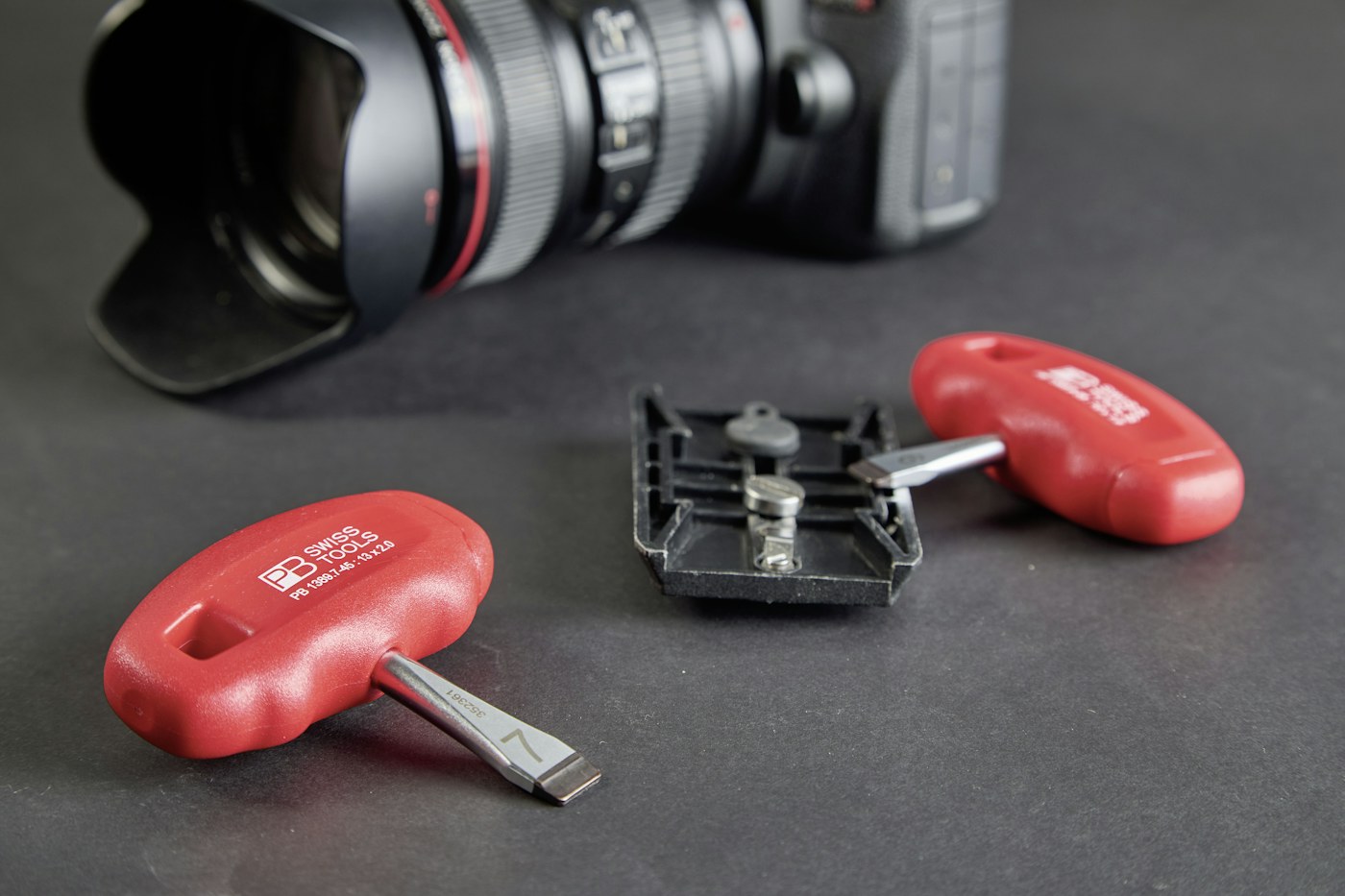 Precision tools arranged beside a camera lens on a work surface
